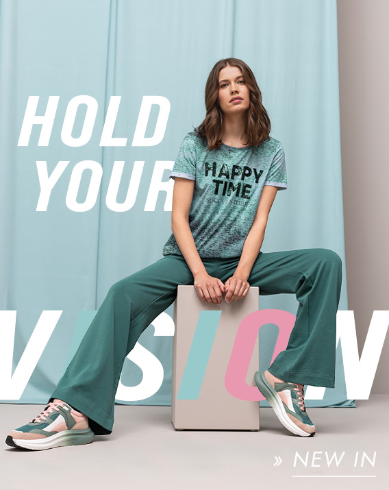 Model trägt Outfit aus der Kollektion Hold Your Vision und sitzt auf einem Hocker