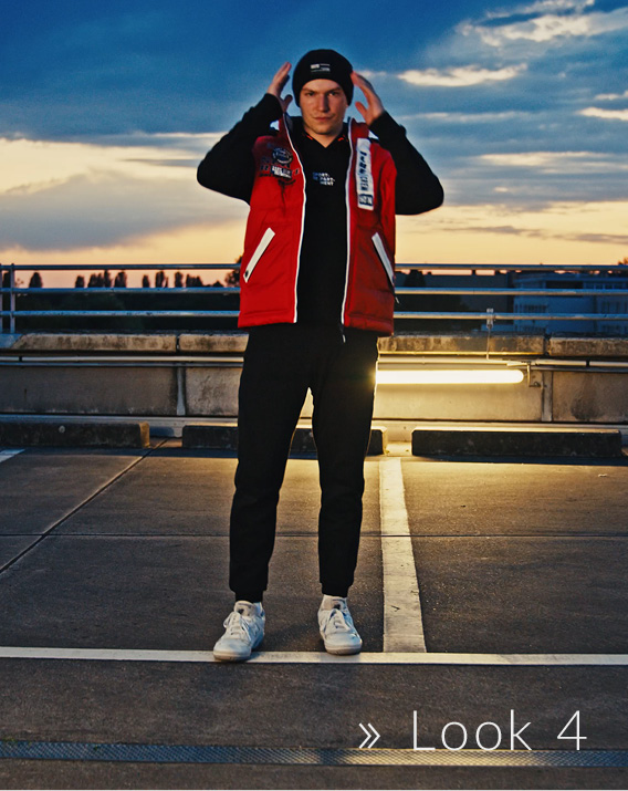 Model trägt rote Jacke und schwarze Beanie